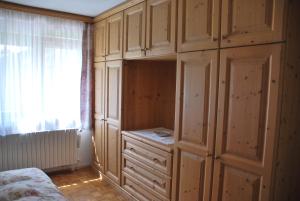 sypialnia z drewnianymi szafkami, łóżkiem i oknem w obiekcie Appartamento Anna & Gino w mieście Sappada