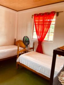 a bedroom with two beds and a window with red curtains at Hotel Caribbean View in Bocas del Toro