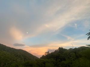 um pôr-do-sol no céu sobre uma floresta de árvores em Unicorn Homestay @ Cameron Highland em Tanah Rata