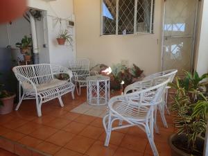 a group of white chairs and tables on a patio at Le cactus guesthouse in Terre Rouge