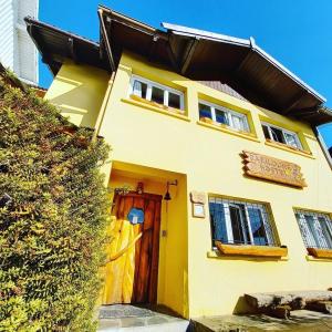 a yellow house with a door and a fence at Bariloche Hostel in San Carlos de Bariloche