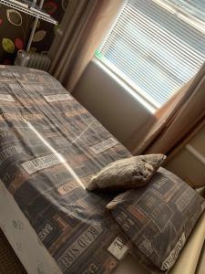 a bed with a pillow next to a window at Cosy 2-Bed Apartment near the beach in Morecambe in Morecambe