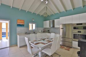 a kitchen with a white table and white chairs at Reflection Z 5 Star Villa in Maho Reef