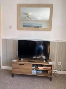a flat screen tv sitting on top of a wooden entertainment center at Cosy 2-Bed Apartment near the beach in Morecambe in Morecambe