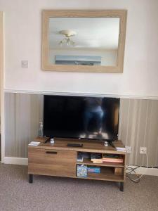 a flat screen tv sitting on top of a wooden entertainment center at 2 Bed Flat - Sleeps 3 - Parking - Wifi in Morecambe