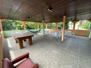 a large patio with a wooden table and chairs at CASA inteira entre Guaratiba e Campo Grande, Rio de Janeiro, RJ - a 40 min da praia, próximo ao Estádio Miecimo da Silva e Park Shopping-Ideal para descanso, encontros, festa e lazer-3000 m2 in Rio de Janeiro