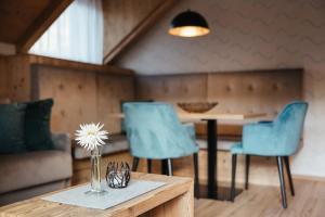 uma mesa com cadeiras azuis e um vaso com uma flor em Alpine Chalet Sauter em San Vigilio Di Marebbe