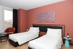 una habitación de hotel con 2 camas y una silla en CX Turin Regina Student&Explorer Place, en Turín