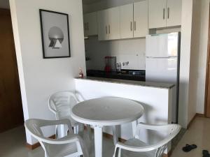 eine Küche mit einem Tisch und Stühlen sowie einem weißen Kühlschrank in der Unterkunft Vista Mar Premium in Ilhéus
