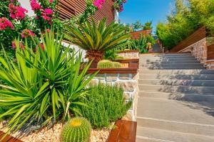 a garden with plants and stairs with pink flowers at Meis Exclusive Hotel in Kaş