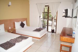 a bedroom with two beds and a desk and a television at AM Amakal Hotel & Park in Santa Cruz Huatulco