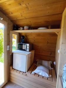 una pequeña cocina en una cabaña de madera con microondas en Les Cabanes d'Hérande, en Fouchères