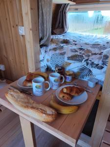 una mesa con platos de pan y tazas de café en Les Cabanes d'Hérande, en Fouchères