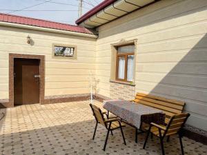 eine Terrasse mit einem Tisch und Stühlen neben einem Gebäude in der Unterkunft Chinara Guest House Airport in Taschkent