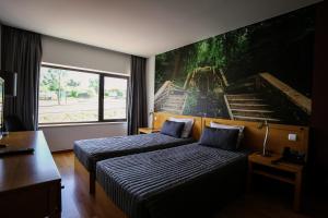 Casal CombaにあるBurguezia do Leitãoのベッドルーム1室(ベッド2台付)が備わります。壁には大きな絵画が飾られています。