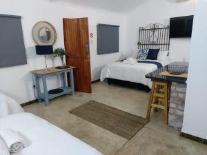 a bedroom with a bed, desk, chair and a lamp at Cock & Bull in Hartbeespoort