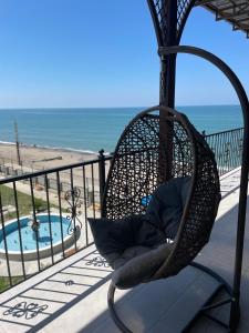 a hanging chair on a balcony overlooking the beach at Hotel Black Sea in Sukhum