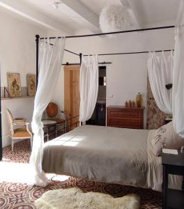 a bedroom with a canopy bed with white curtains at Villa Fontilha in Usclas-lʼHérault