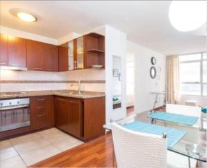 a kitchen with wooden cabinets and a glass table at SyS Suites Nueva San Martin in Santiago