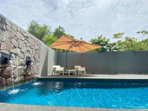 a table and chairs with an umbrella next to a swimming pool at LeGrace Villa Langkawi Private Pool in Pantai Cenang