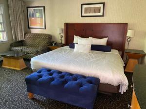 a hotel room with a large bed and a blue ottoman at The Black Mountain Inn in Brattleboro