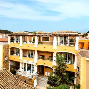 un edificio giallo con scale di fronte di Janas Hotel a Villasimius