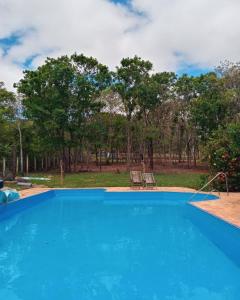 a blue swimming pool in a yard with trees at Espaço Mascattes Pousada in Serra do Cipo