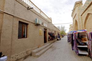 une rue étroite avec un bâtiment et une boutique dans l'établissement Polvonnazir Guest House, à Khiva