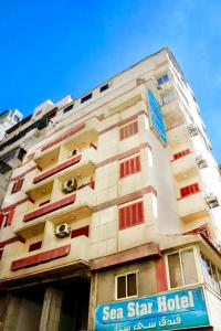 um edifício alto e branco com uma placa à frente. em Sea Star em Alexandria