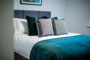 a bed with green and white pillows on it at Modern House with FREE Private Parking, WIFI & Netflix in Stratford-upon-Avon