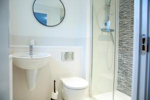 y baño con aseo, lavabo y espejo. en Modern House with FREE Private Parking, WIFI & Netflix, en Stratford-upon-Avon