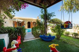 a backyard with a play area with toys on the grass at Villa Hara in Ayía Paraskeví
