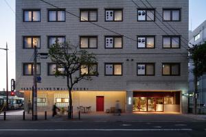 un edificio en una calle con gente caminando delante de él en UNPLAN Fukuoka en Fukuoka