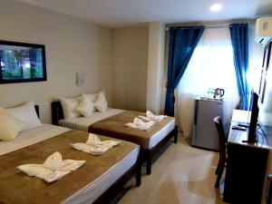 a room with two beds and a desk and a window at Venezia Suites Hotel Iloilo in Iloilo City