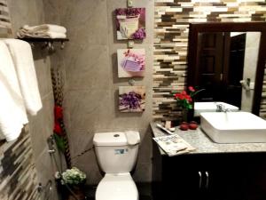 a bathroom with a white toilet and a sink at Venezia Suites Hotel Iloilo in Iloilo City