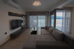 Mrs Grey Luxury Villa في ميغانيسي: غرفة معيشة مع أريكة كبيرة وتلفزيون
