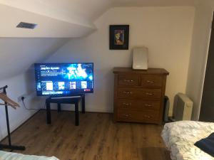 a bedroom with a television and a dresser with a bed at Central Lisburn Duplex Apartment No Parties in Lisburn