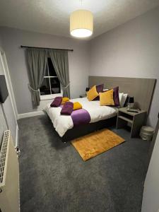sypialnia z dużym łóżkiem z fioletowymi i żółtymi poduszkami w obiekcie The castlegate arms w mieście Penrith