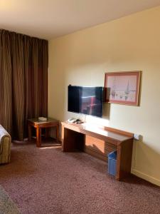 um quarto de hotel com uma televisão de ecrã plano numa secretária em Top Hotel Apartments em Al Ain