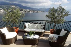 patio z krzesłami i stołem z widokiem na wodę w obiekcie Villa del Mar w mieście Herceg Novi