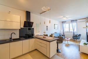 a kitchen with white cabinets and a living room at Flexible SelfCheckIns 25 - Zagreb - Garage - Loggia - New - Luxury in Zagreb