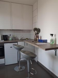 una cucina con armadi bianchi, bancone e sgabelli di Apartman Sweet penthouse self check-in a Karlovac
