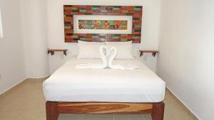 Una cama blanca con dos toallas blancas encima. en El Fuerte Beach Apartments, en Mahahual