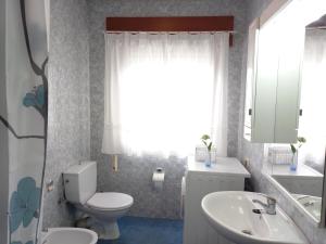 a bathroom with a toilet and a sink and a mirror at PISO AMPLIO A 100 M DE LA PLAYA in Foz +18 photos