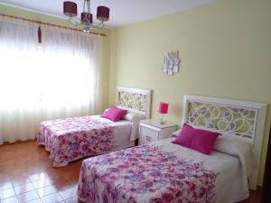 een slaapkamer met 2 bedden met roze lakens en een raam bij PISO AMPLIO A 100 M DE LA PLAYA in Foz