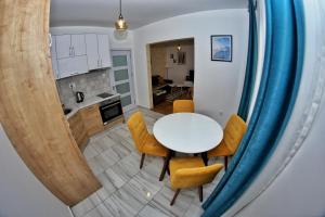 eine Küche und ein Esszimmer mit einem weißen Tisch und gelben Stühlen in der Unterkunft Apartmani Zecevic Niksic in Nikšić