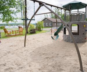 ein Spielplatz im Sand mit einer Schaukel in der Unterkunft Les Chalets Baie Cascouia in Larouche