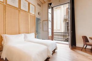 a white bed sitting in a room next to a window at Sonder DO Plaça Reial in Barcelona
