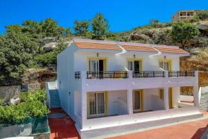 a large white house with a hill in the background at Coloma Apartments Pefkos in Pefki