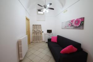 a living room with a black couch and pink pillows at B&B Don Gino in Monopoli